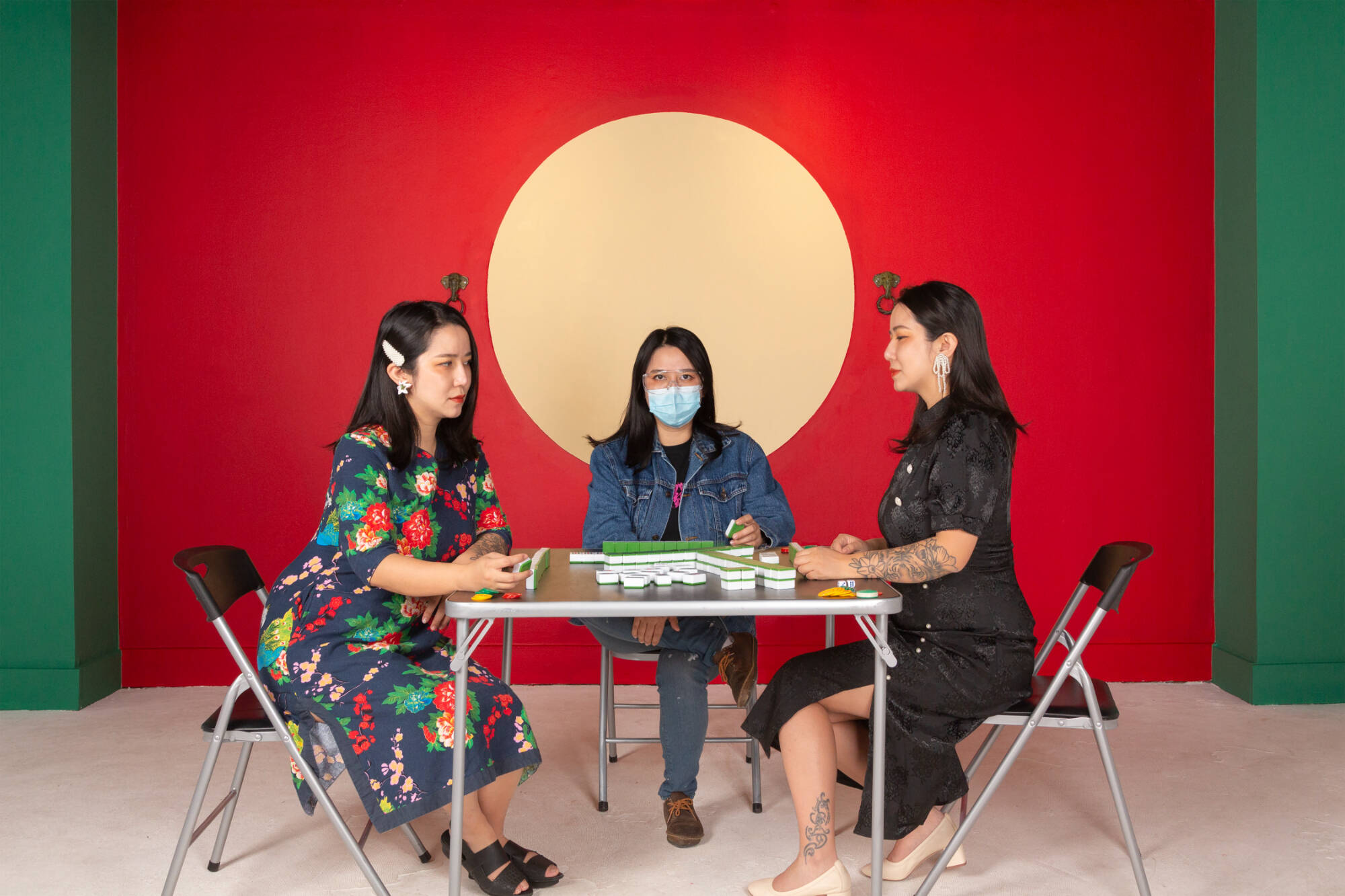 Photograph of three women sitting around a table playing mahjong